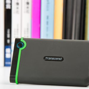 Transcend StoreJet rugged external hard drive connected to a laptop showcasing the one-touch auto-backup button